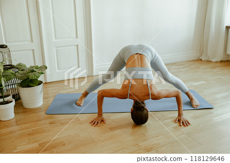 A Flexible Woman Engaged in Practicing Yoga in a Bright and Inviting Indoor Space 118129646