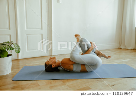 A woman practicing yoga in a calming indoor space, enhancing her wellbeing and tranquility 118129647
