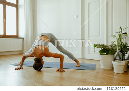 A woman practices yoga at home, embracing peace, inner serenity, and deep focus A woman practices yoga at home, embracing peace, inner serenity, and deep focus 118129651