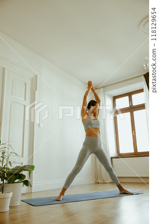 A Woman Engaging in Yoga Practice Within a Beautifully Bright and Minimalist Space 118129654
