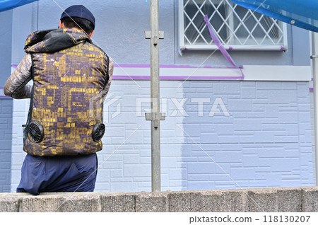 A scene of a craftsman painting an exterior wall. Painter. Exterior wall painting work. 118130207