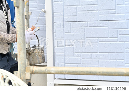 A scene of a craftsman painting an exterior wall. Painter. Exterior wall painting work. Siding. A scene of a craftsman painting an exterior wall. Painter. Exterior wall painting work. Siding. 118130296