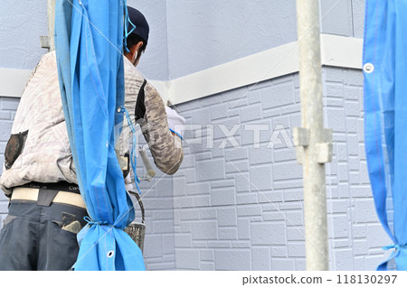 A scene of a craftsman painting an exterior wall. Painter. Exterior wall painting work. Siding. 118130297