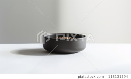 A black bowl sits on a clean, minimalist surface, filled with seeds 118131394