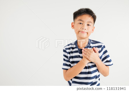 Happy young kid boy in casual clothes holding hands at chest close to heart meditation and smiling in studio short isolated on white background, primary child believe faith and love gratitude Happy young kid boy in casual clothes holding hands at chest close to heart meditation and smiling in studio short isolated on white background, primary child believe faith and love gratitude 118131941