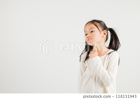 Portrait Asian kid girl deep in thought, standing with chin in hand, pondering a question. Studio shot isolated on white with ample copy space, kindergarten child portraying contemplative expression 118131943