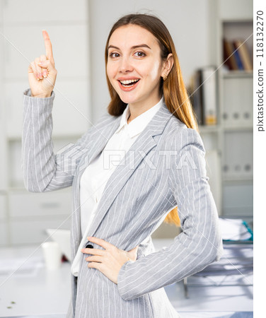 Female office manager standing and pointing finger up 118132270