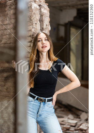 Young woman in jeans and black t-shirt posing inside ruined house 118132360