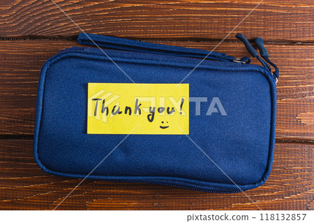 A small blue case with a yellow thank you label 118132857