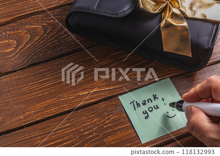 A person is writing a thank you note on a piece of paper A person is writing a thank you note on a piece of paper 118132993