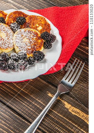 Cottage cheese pancakes with fresh blackberries, powdered sugar on a plate 118133020