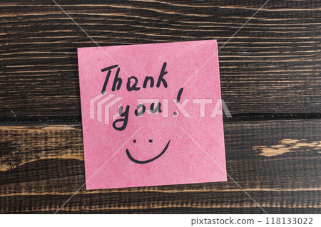 Thank you word with emoticon on pink paper on wooden table 118133022