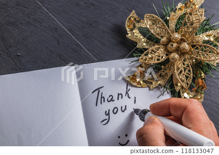 A person writes thanks on a piece of paper, with a decorative flower on the side A person writes thanks on a piece of paper, with a decorative flower on the side 118133047