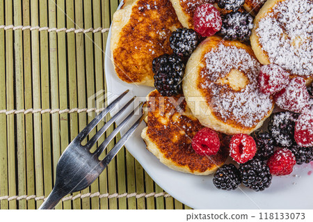 Cottage cheese pancakes with fresh raspberries, blackberries and powdered sugar 118133073