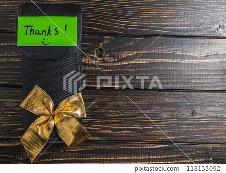 A small black soft box with a gold bow and a green thanks you label 118133092