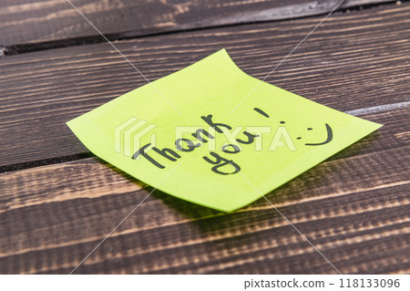 Thank you word with emoticon on green paper on wooden table Thank you word with emoticon on green paper on wooden table 118133096