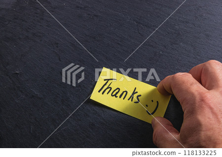 The man is holding a piece of paper with the word thank you in his right hand 118133225