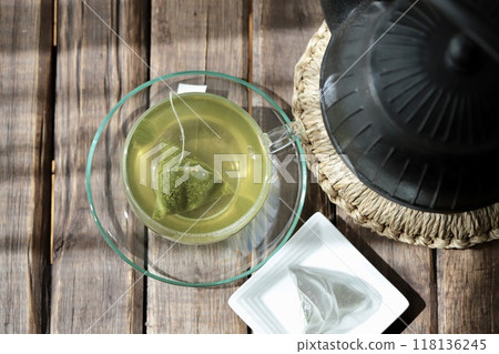 Hot green tea brewed in a triangular tea bag and an iron kettle Hot green tea brewed in a triangular tea bag and an iron kettle 118136245