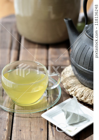 Hot green tea brewed in a triangular tea bag and an iron kettle 118136248