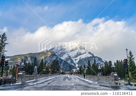 Banff Avenue in snowy autumn sunny day. Snow-covered Cascade Mountain with blue sky and white clouds in the background. Banff National Park, Canadian Rockies. Banff, Canada 118136411