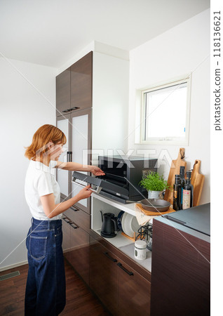 Woman operating a microwave cooking 118136621