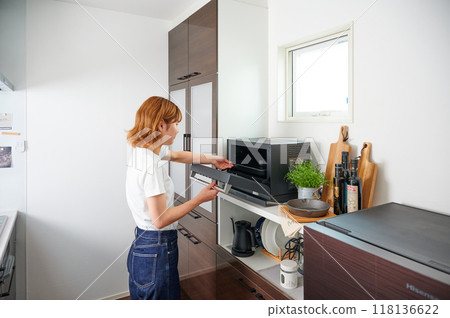 Woman operating a microwave cooking Woman operating a microwave cooking 118136622