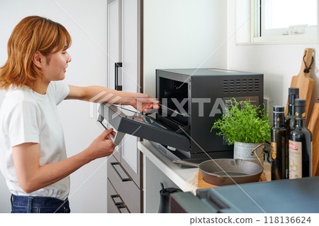 操作微波爐烹調的婦女 操作微波爐烹調的婦女 118136624