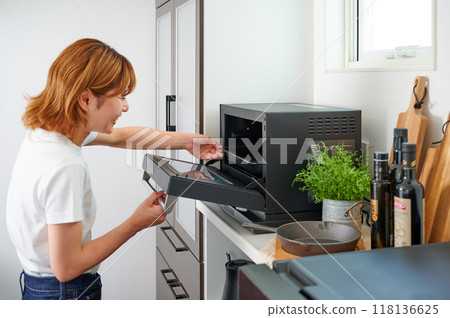 Woman operating a microwave cooking Woman operating a microwave cooking 118136625