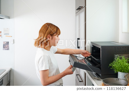 Woman operating a microwave cooking Woman operating a microwave cooking 118136627