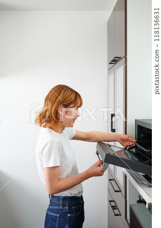 Woman operating a microwave cooking Woman operating a microwave cooking 118136631