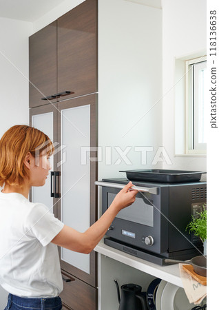 Woman operating a microwave cooking Woman operating a microwave cooking 118136638