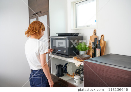 Woman operating a microwave cooking Woman operating a microwave cooking 118136646