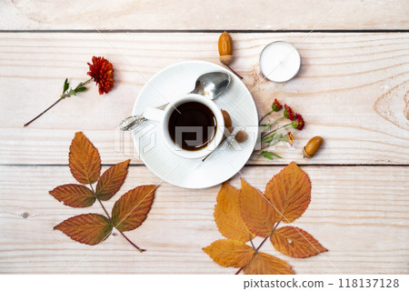 Autumn, fall leaves, hot steaming cup of coffee and a warm scarf on wooden table background. Seasonal, morning coffee, Sunday relaxing and still life concept. 118137128