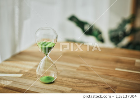 Glass hourglass on a wooden table 118137304