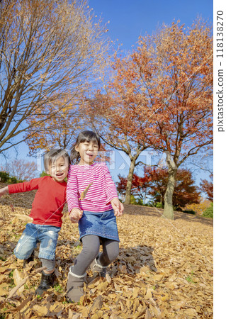 Older sister and younger brother playing in a park with autumn leaves Older sister and younger brother playing in a park with autumn leaves 118138270