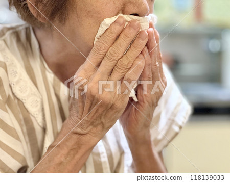 老婦人雙手拿著紙巾摀住嘴 老婦人雙手拿著紙巾摀住嘴 118139033