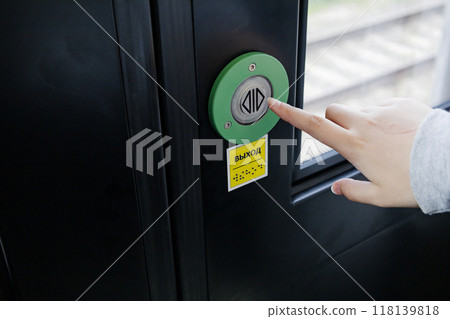 A person is pressing a green button located on a door surface, the inscription in Russian is the exit A person is pressing a green button located on a door surface, the inscription in Russian is the exit 118139818