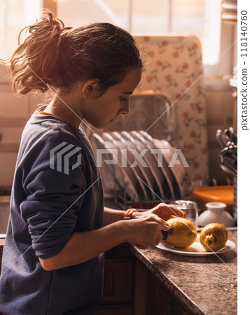 Young Girl Slicing Lemons in Kitchen for Juice Young Girl Slicing Lemons in Kitchen for Juice 118140760