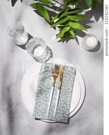 Festive table setting with white plates, glasses and candle for a celebration with eucalyptus Festive table setting with white plates, glasses and candle for a celebration with eucalyptus 118142162