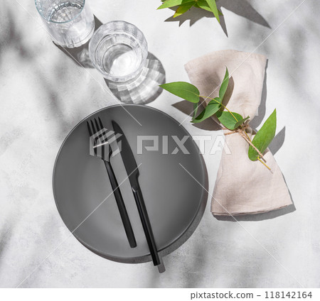 Festive table setting with dark grey plate and glasses for a celebration with eucalyptus branches Festive table setting with dark grey plate and glasses for a celebration with eucalyptus branches 118142164
