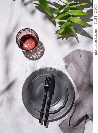 Festive table setting with dark grey plates and glass for a celebration with eucalyptus branches Festive table setting with dark grey plates and glass for a celebration with eucalyptus branches 118142166
