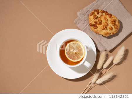 A cup of tea with lemon and homemade cookies on napkin on a brown background. Healthy and cozy drink 118142261