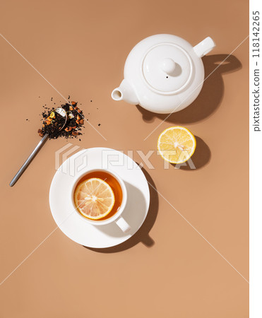 Creative layout of a cup of herbal tea with lemon and teapot on a brown background 118142265