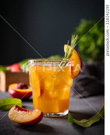Peach tea with ice and rosemary on a glass. Vegan homemade healthy drink on a dark background Peach tea with ice and rosemary on a glass. Vegan homemade healthy drink on a dark background 118142295