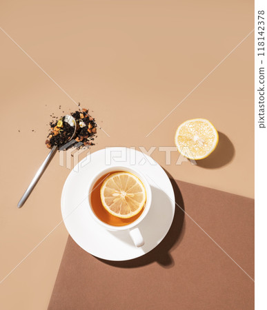 Creative flat lay of a cup of tea with lemon on a brown background with hard shadow.  118142378