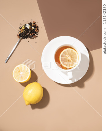 Creative flat lay of a cup of tea with lemon on a brown background with hard shadow. 118142380