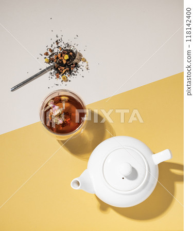Creative flat lay of a glass cup of herbal tea with rose flowers on a yellow and white background  118142400