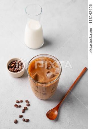 Vegan iced coffee latte in a tall glass with soy milk on a light background with coffee beans Vegan iced coffee latte in a tall glass with soy milk on a light background with coffee beans 118142406