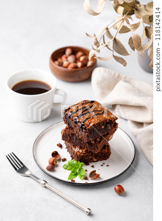 A stack of chocolate brownies with mint, hazelnuts and salted caramel on a white plate  118142414
