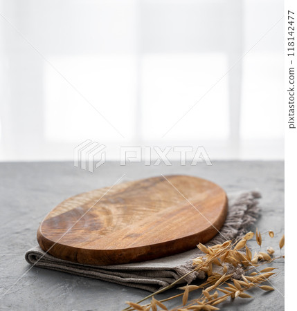 Empty cutting board on a blue textured background in front of a window with a dry branch Empty cutting board on a blue textured background in front of a window with a dry branch 118142477